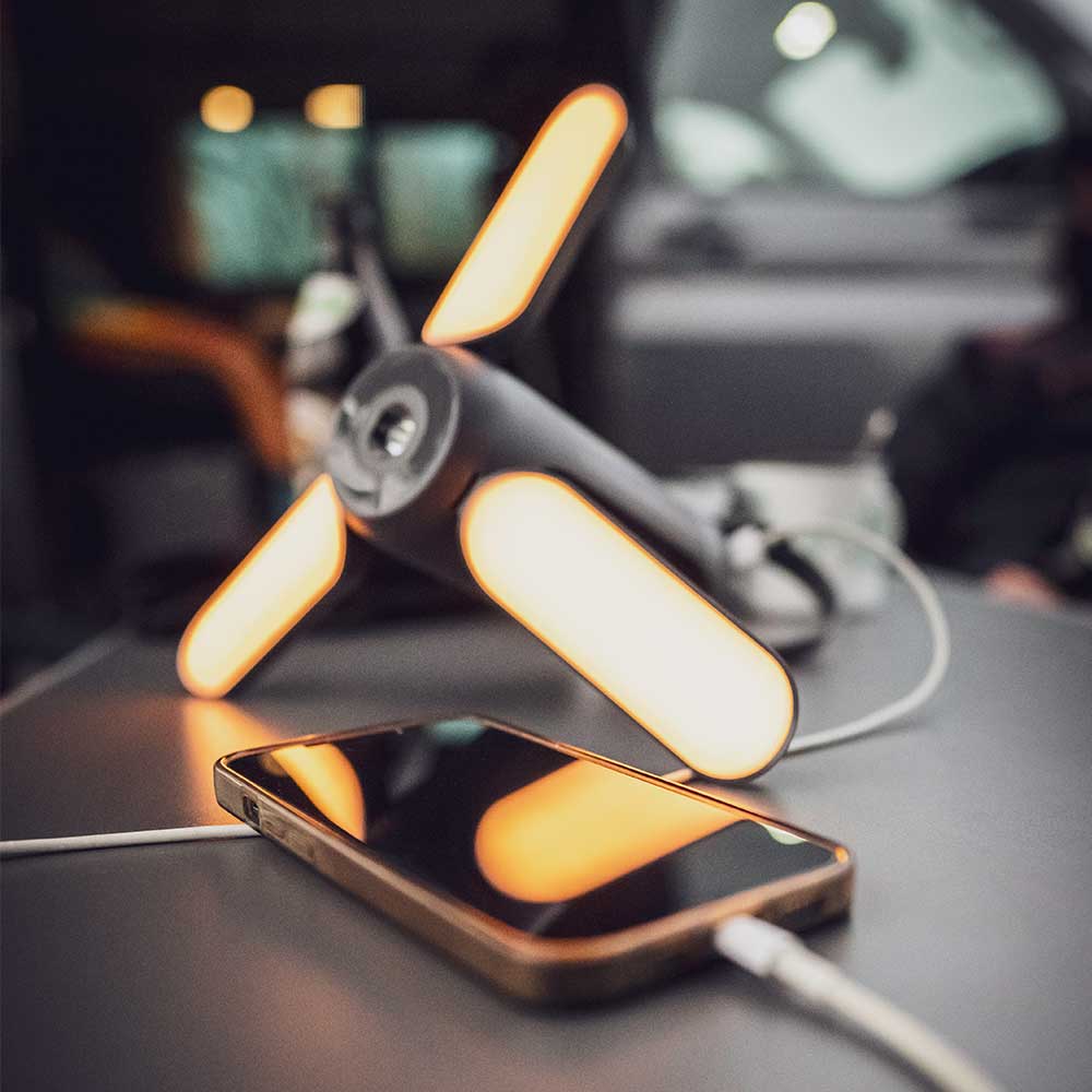 Ein tragbares Camping-Licht ist eingeschaltet und wird als Powerbank eines Handys benutzt.